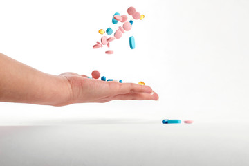Colorfull medicine pills jumping off left hand. blue, rose and yellow medicines and vitamins