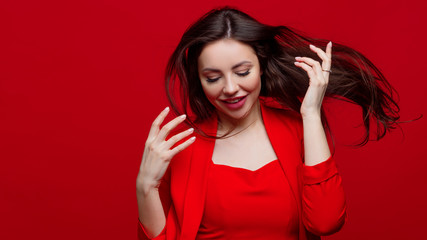 Stylish young woman in a red suit on a red background.