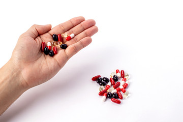 Colorfull medicine pills in left hand. red, white and black medicines and vitamins