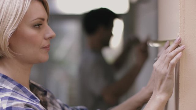 Adult couple measuring wall in new home