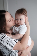 Smiling mother holding her newborn baby daughter at home.