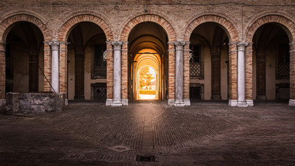 Arches of Palace Venieri with golden hour sunlight shining in through the entrance doorway, Recanati, Italy