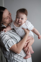 Smiling mother holding her newborn baby daughter at home.