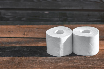 Two rolls of toilet paper lying on wooden boards
