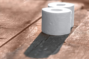 Two rolls of toilet paper lying on wooden boards