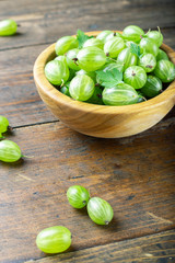 Sweet fresh gooseberry berry in a bowl on wood background.