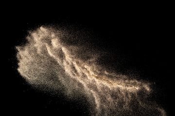 Brown colored sand splash.Dry river sand explosion isolated on black background. Abstract sand...