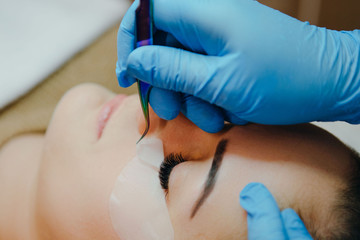 Close-up of yelash extension procedure in beauty salon. Woman eye with long eyelashes.