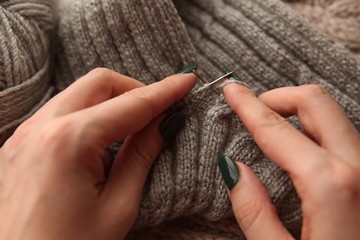 Obraz premium Knitting - young womans hands using knitting needles and grey wool roll. woman hands knitting