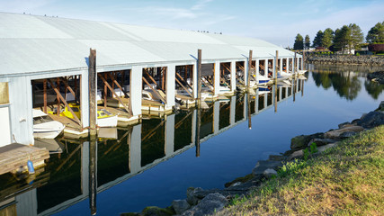 blue boathouses and boats reflected in the water of the bay, sunny day on the pacific coast. British Columbia, Canada.