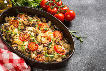Baked meat with vegetables on black table.