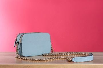 Stylish woman's bag on wooden table against pink background