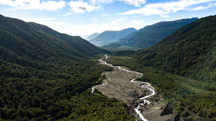 Aerial view on green valley with river stream surrounded by mountains. Nahuel Huapi National Park in Patagonia, Argentina  - obrazy, fototapety, plakaty