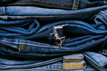 Stack of jeans on a concrete background. Selvedge jeans. Copy space.