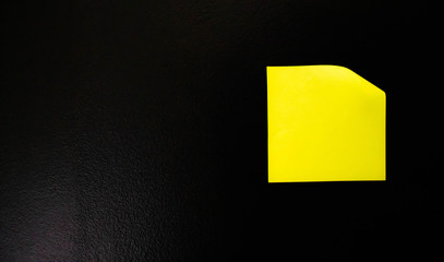 Yellow office sticker on a black wall.