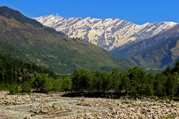 Snow clad himalayas viewed from The Beas River in Manali from Leh - manali highway in summer morning of May, India.Himachal Pradesh