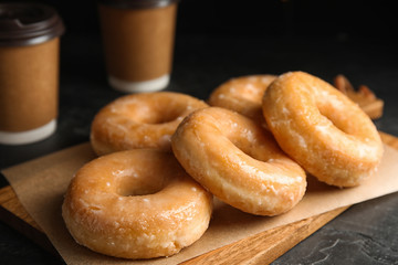 Delicious glazed donuts on wooden board, closeup