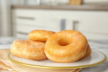 Delicious glazed donuts on marble table, closeup
