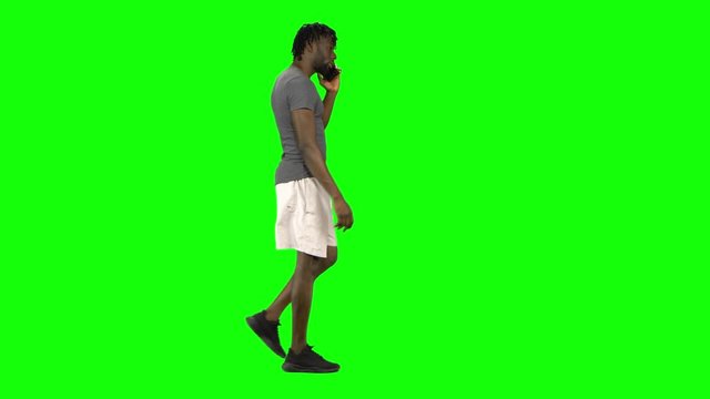 African american man walking and talking on the mobile phone at Green Screen, Chroma Key. Profile view.