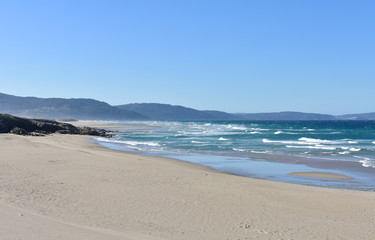 Wild Atlantic Ocean beach with furious sea, waves breaking and blue sky. Arteixo, Coruña, Galicia, Spain.