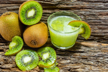 Fruits and Kiwi juice fresh and in halves on a woody background