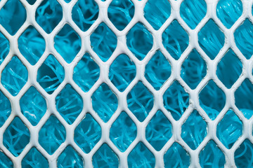 Metal enameled grid. abstract background. blue cloth behind the metallic grate