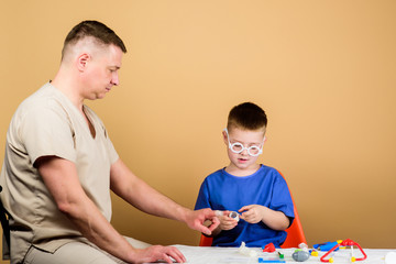 Medical examination. Boy cute child and his father doctor. Hospital worker. First aid. Medical help. Trauma and injurie. Medicine concept. Kid little doctor sit table medical tools. Health care