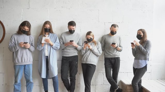 Group of young caucasian people in protective medical mask, they take care of health, afraid of coronavirus infection. COVID-19 disease global problem. People stand in a line