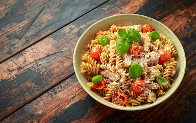 Healthy Chicken, fusilli pasta with tomatoes, basil and parmesan cheese. on wooden table.