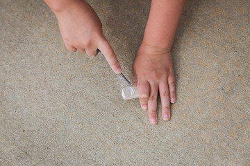 Child carving sidewalk chalk with plastic knife