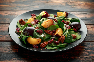 Vegan plums salad with cranberry, pumpkin seed, pecans nuts, spinach and mustard dressing