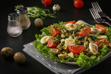 Healthy organic salad with chicken, cherry tomatoes, quail eggs, black olives and microgreens peas against a dark background