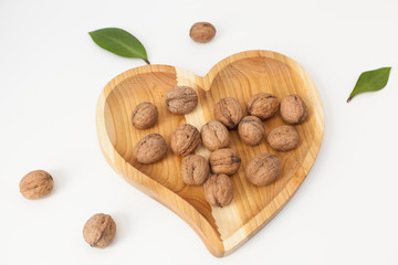 handmade wooden heart-shaped plate with nuts on the table, top view