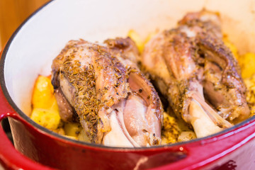 Braised lamb shanks with cumin seeds in red casserole closeup