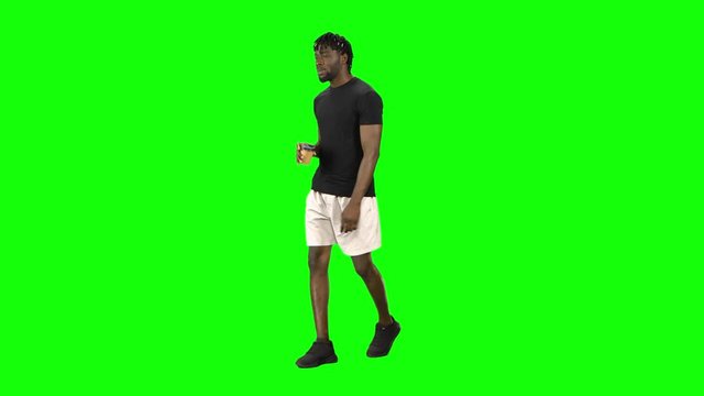 African american man is walking and drinking coffee at Green Screen, Chroma Key.
