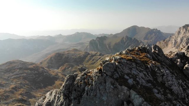 Aerial panoram view of girl rises on a mountain ridge. Beautiful view of the peaked tops of Durmitor in Montenegro
