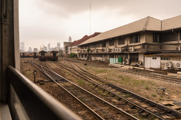 Obraz premium Trains on a hazy day in central train station. Skyscrapers in distance. Arrival from Don Mueang International Airport
