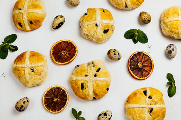 Easter background with cross buns, orange, mint and quail eggs