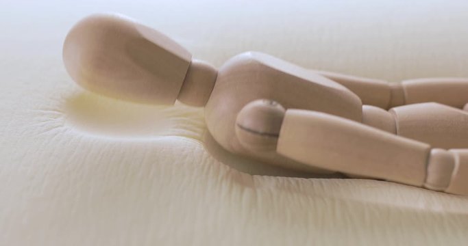 Uomo di legno sta testando a dormire nel nuovo materasso in poliuretano con tecnologia in memory foam.