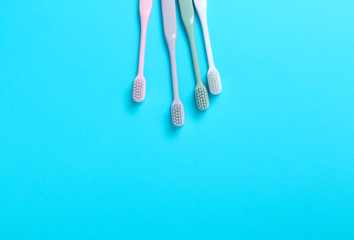 Pink, green, white and gray toothbrushes on blue background. Taking care of teeth, dental concept. Flat lay photo, copy space, top view.
