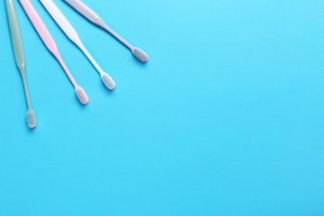 Pink, green, white and gray toothbrushes on blue background. Taking care of teeth, dental concept. Flat lay photo, copy space, top view.