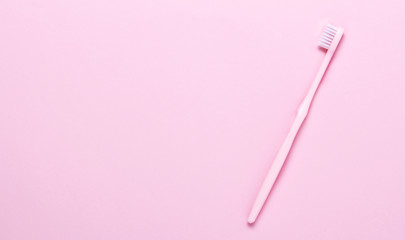 Pink toothbrush on pink background. Taking care of teeth, dental concept. Flat lay photo, copy space, top view,minimalism.