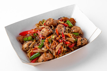 Udon, noodles with minced meat sausages with vegetables cooked in a wok packed in a paper plate for take away or food delivery isolated on a white background.