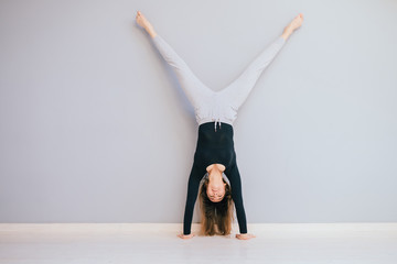 Fit woman doing handstand near wall. Athlete standing on hands Concept balance sport fitness