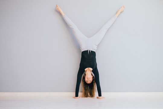 Fit woman doing handstand near wall. Athlete standing on hands Concept balance sport fitness