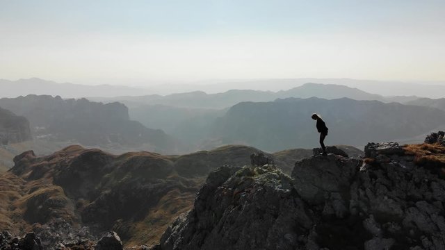 Girl standing on a mountain ridge. Beautiful aerial view of the peaked tops of Durmitor in Montenegro