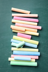 Pieces of color chalk on greenboard, flat lay