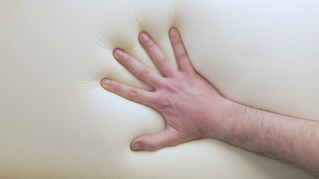 Mano sta toccando un materasso in poliuretano con tecnologia memory foam.