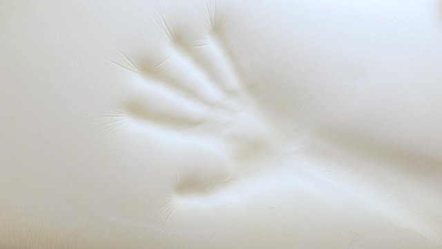 Mano sta toccando un letto in poliuretano con tecnologia memory foam.