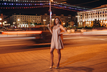 a young girl in a summer dress walks around the city at night